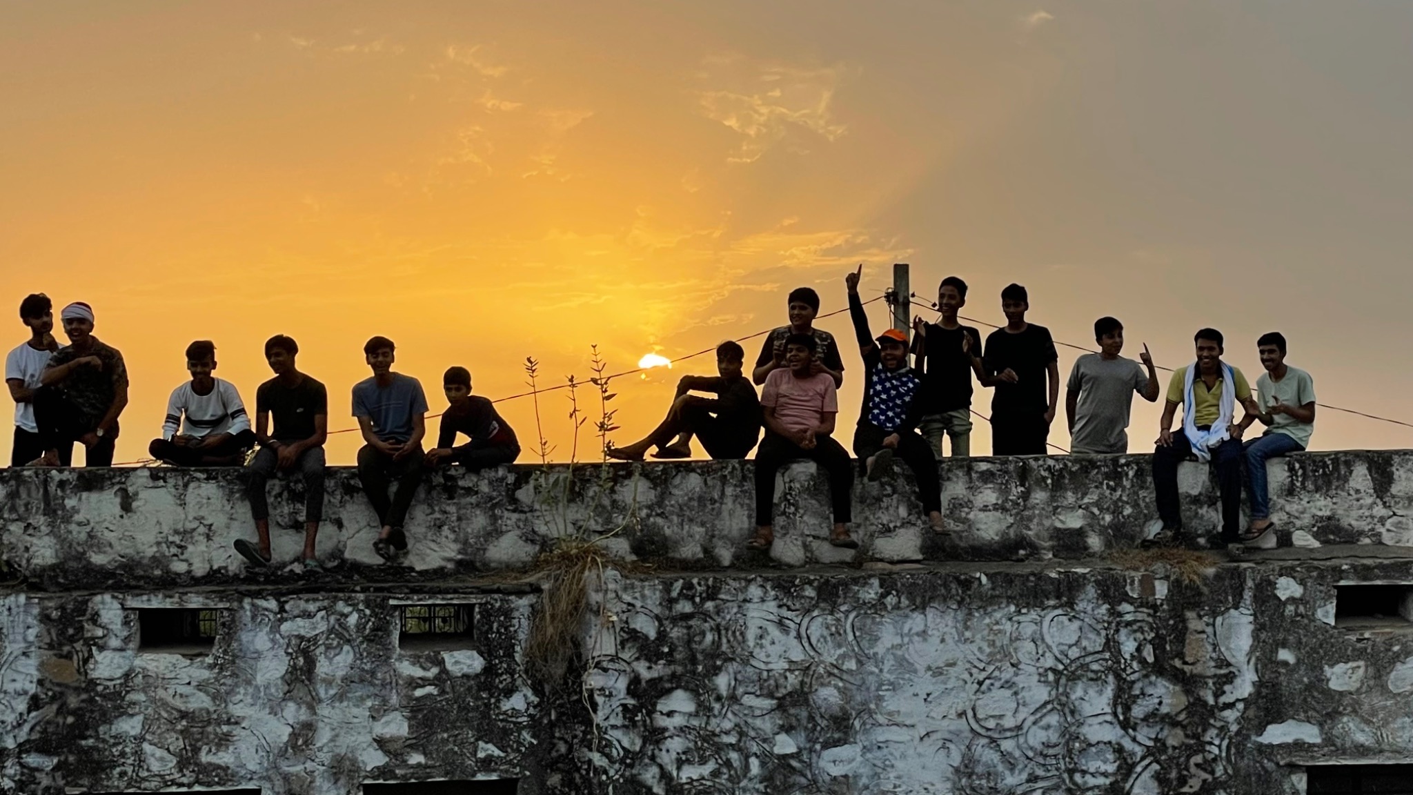 A group of local people gathered on a wall at sunset during the Rennervations production in India